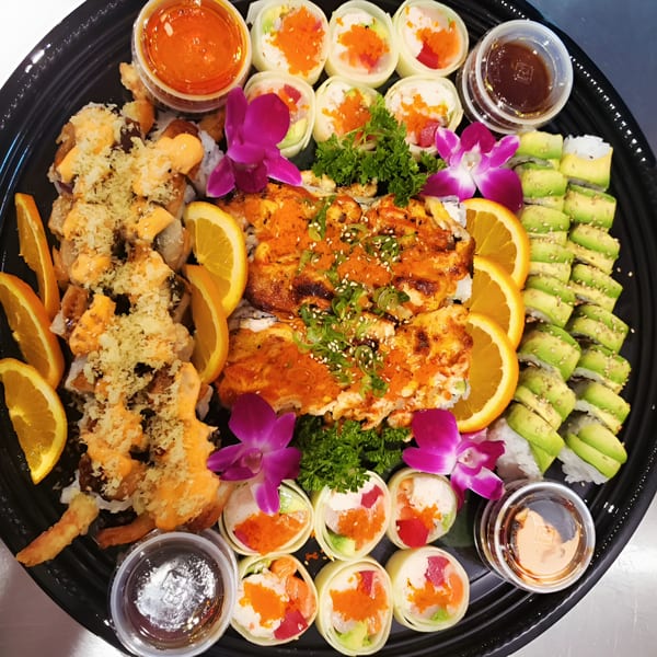 A large Kin Sushi platter with various sushi rolls, orange slices, sauces, and purple orchids.