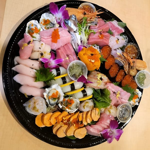 Kin Sushi's large platter of sashimi, nigiri, oysters, uni, and other seafood, garnished with orchids.